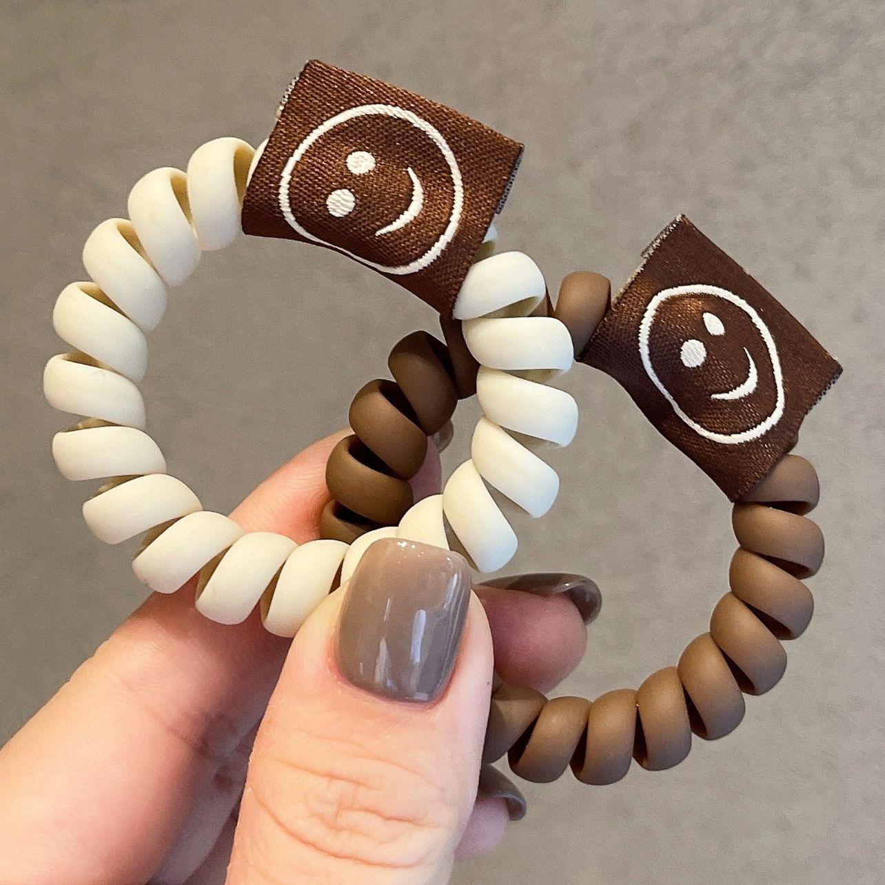 Achieve a cute look with our Milk Tea Frosted Hair Circle, featuring a smiley face rope for girls' hair.